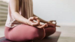 Close-up of a woman meditating indoors, practicing yoga for wellness and relaxation.